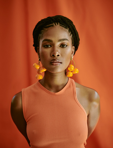 Beautiful black woman standing and looking at the camera shot against orange background. stock photo