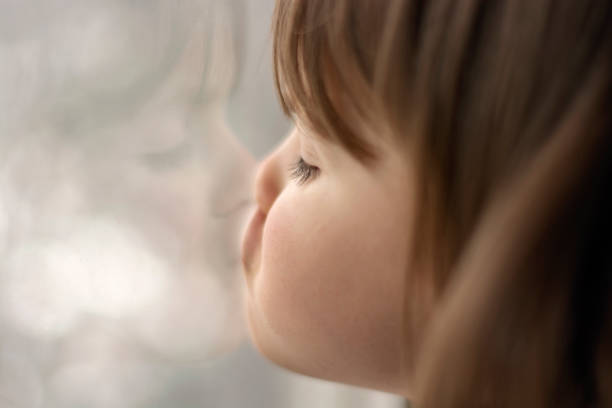 istock Cute little girl looking through window 1618298776