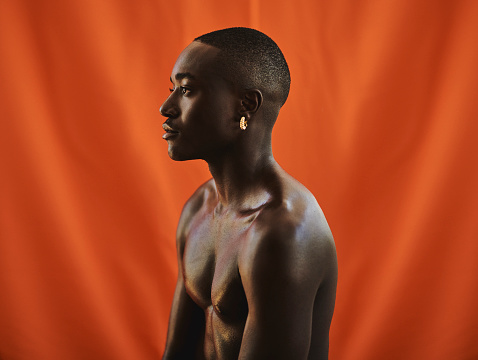 side profile shot of a handsome African young man in front of a orange backdrop. stock photo, copy space