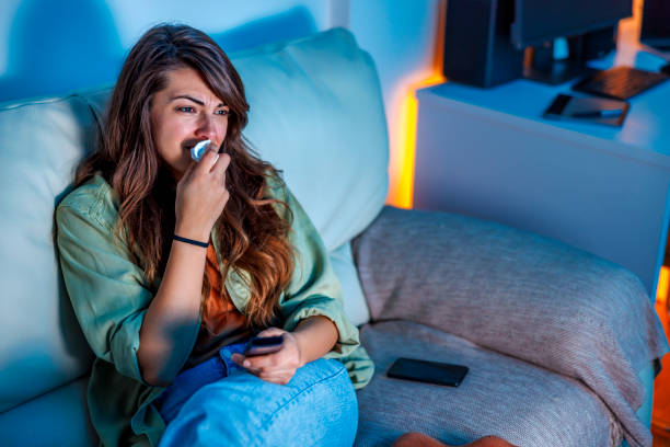 Emotional woman crying while watching sad movie on TV at home stock photo
