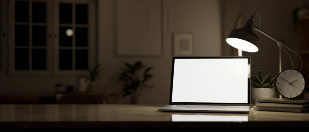 istock Workspace at night, a laptop mockup, a table lamp, and decor on a desk. 1618316186