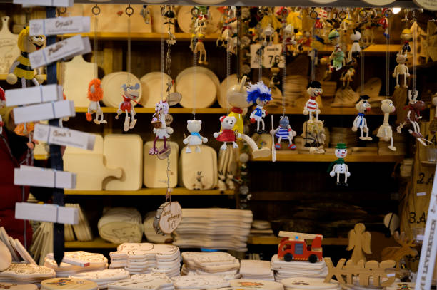 Bonn, Germany - December 5, 2022: Bouncy spring wooden figurines hanging in a Christmas market vendor's stall with various other wooden decorative, seasonal items in the background