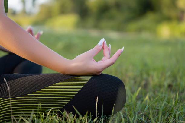istock Meditation in nature for a healthy lifestyle: a girl performs complex asanas while sitting on a green lawn close-up 1618329393