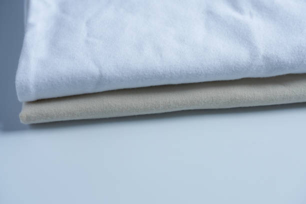 istock Close-up of a stack of white and beige clothes on a light background. 1618359189