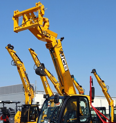 Pradamano, Italy. August 14, 2023. Booms of JCB excavators and telehandlers against blue sky in the official dealership of tne british manufacturer.