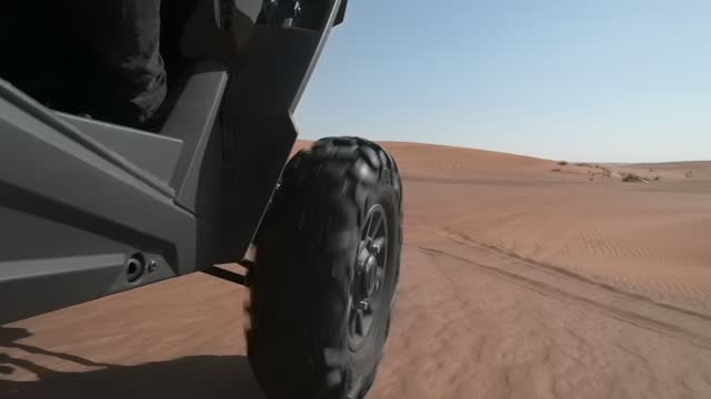 An SUV drives over sand dunes in the Dubai desert