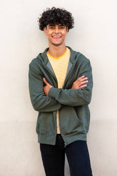 istock smiling young handsome man with arms crossed by white wall 1618385184