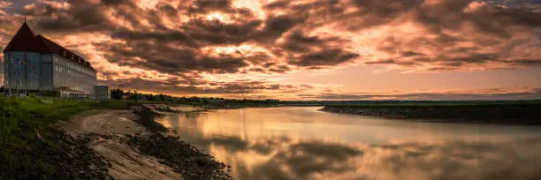 Photo of Petitcodiac River with dramatic sunrise cloudscape at Bore Park or Parc Bore Riverfront Walk, a popular place to watch the tidal bore in Moncton, New Brunswick, Canada