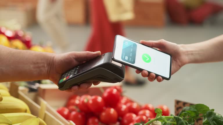 Consumer Buying Organically Sourced Farm Produce Using a Digital Credit Card to Pay with a Smartphone Software Through Contactless Online NFC Technology on a Bank Point-Of-Sale Terminal