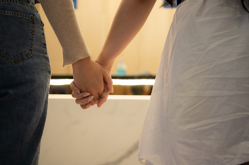 Close-up of a couple holding hands in a box office waiting to buy movie tickets