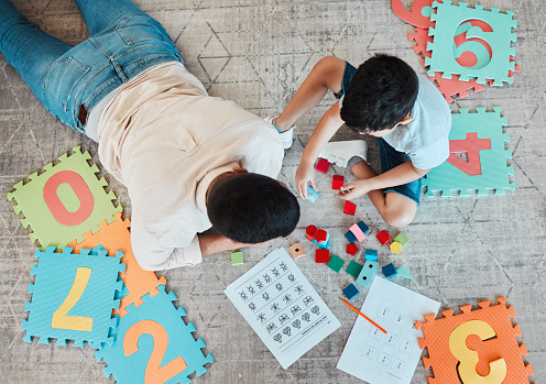Building blocks, above or father with kid on the floor for learning, education or child development at home. Family, play or dad enjoying bonding time in living room with boy or toys doing homework