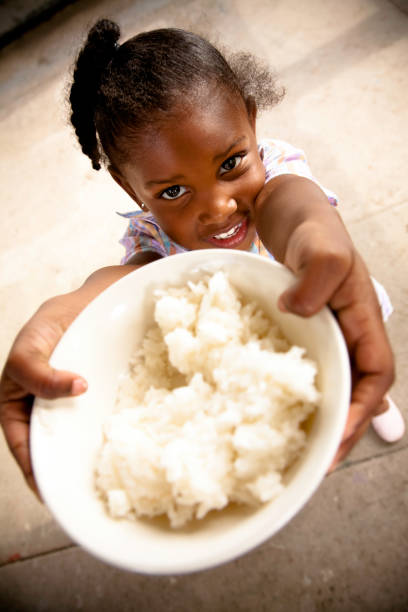 Young girl holding up a bowl of rice Young girl holding up a bowl of rice. meals on wheels photos stock pictures, royalty-free photos & images