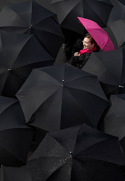 женщина, глядя вверх из-под зонтик - standing out from the crowd individuality umbrella contrasts стоковые фото и изображения