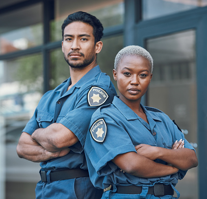 Portrait, serious and arms crossed with the police force standing outdoor in the city for law enforcement. Safety, security or surveillance with a man and woman officer on patrol in an urban town