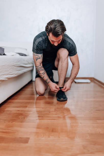 istock Young man prepares for run, tying shoes 1618475298