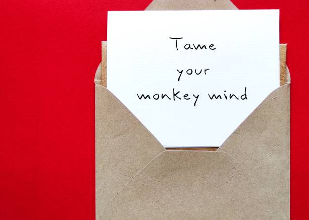 istock Envelope on red background with note written TAME YOUR MONKEY MIND, Buddhism mindfulness practice to control distraction wandering mind which unfocused jumping from thought to thought like monkey 1618483159