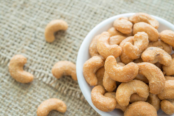 istock Salted cashew nuts in dessert bowl on sackcloth background. 1618483538