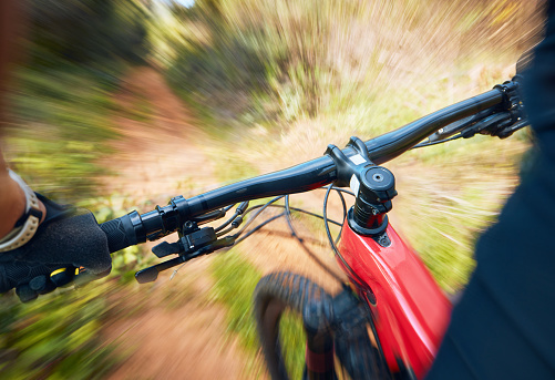 Bike, cycling and motion blur with a sports person holding handle bars while riding outdoor closeup pov. Bicycle, fitness and speed with a cyclist or athlete mountain biking in nature during summer