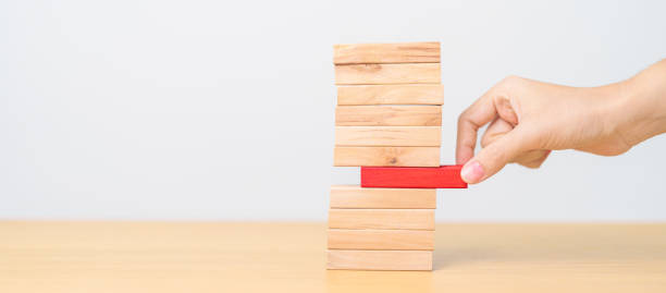istock woman hand pulling wood domino blocks on table. Crisis, fall Business, Risk management, Economic recession, Strategy and solutions concept 1618498332