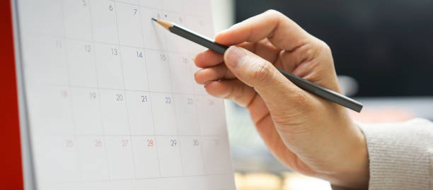istock close up on businessman hand use pencil to write important appointments or note to remember on calendar to mark date for business lifestyle concept 1618511058