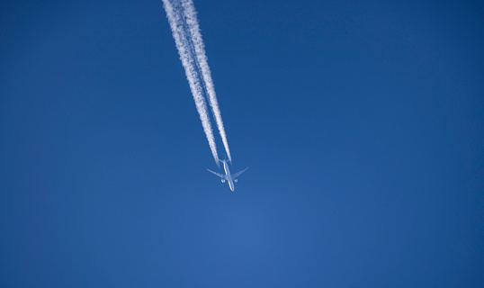 Airplane with condensation trails in blue sky