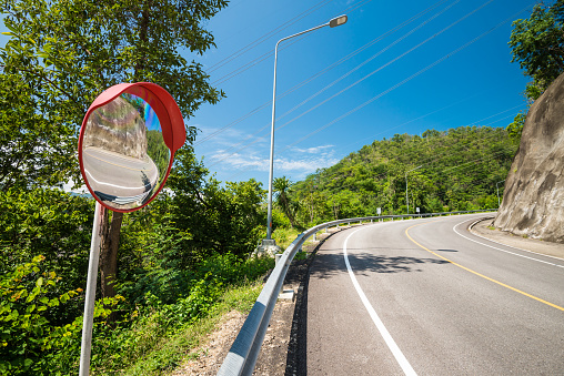 Up hill road turning on the mountains with outdoor traffic convex mirror. Transport and traffic concept.