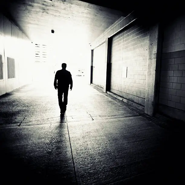 man walking through downtown alley into the light.