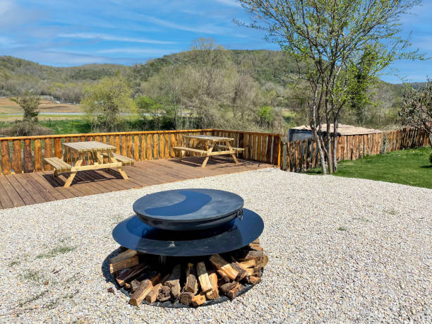 istock Camping site with fire pit and wooden desks and deck, mountain view in the background 1618526971