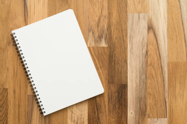 Flat lay of open blank spiral notepad or notebook on wooden table background.