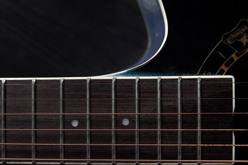 guitar neck with strings close-up on a black wooden background, still life