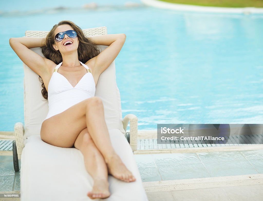 幸せな若い女性のスイムスーツに楽しく-ロングプールサイドの寝椅子 - サングラスのロイヤリティフリーストックフォト