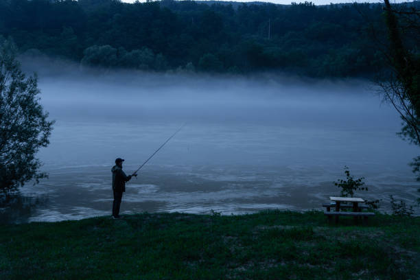Man fishing on the mountain river at evening