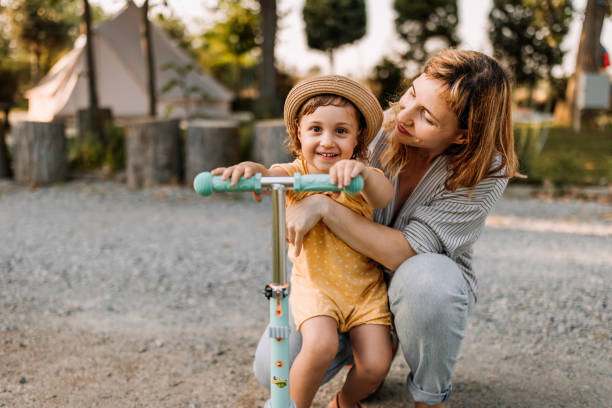 istock Mother and daughter having fun with push scooter at camping 1618634312
