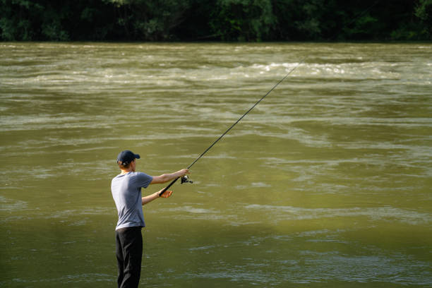 a man with a fishing rod on the river bank is fishing