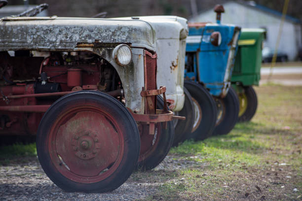 Side view of parked old vintage collection of tractors in a row next to road