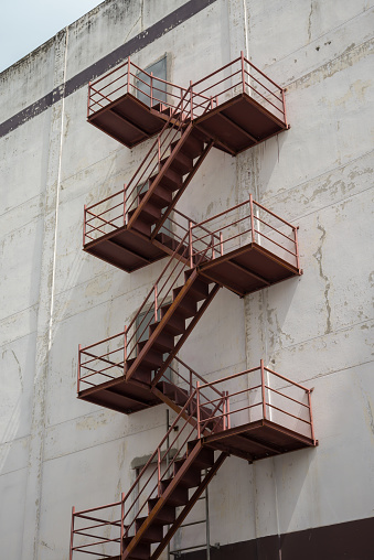 Apartment building exterior with steel fire escape ladder. Safety system and evacuation in building concept.
