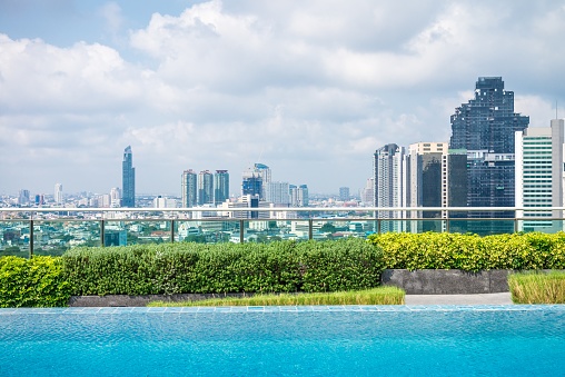 Outdoors rooftop swimming pool with city view background. City life, relaxation concept.
