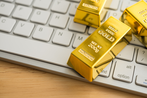 Gold bars on white keyboard computer background. Gold commodity trading market online investment concept. Digital technology for safe haven asset trading.