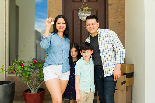 Hispanic family receiving the new house keys for their beautiful home after buying real estate looking happy moving in