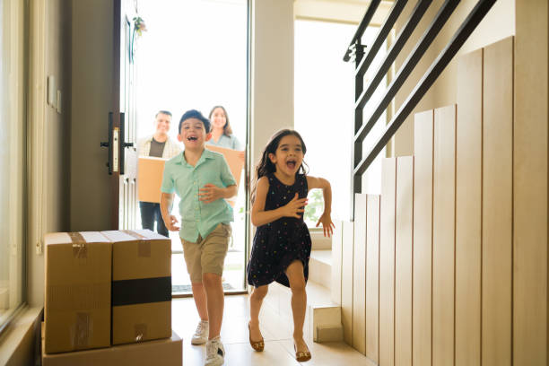 Excited kids moving in and laughing while running in their new home Very happy children running looking excited about moving in into a new house with mom and dad carrying boxes home ownership stock pictures, royalty-free photos & images