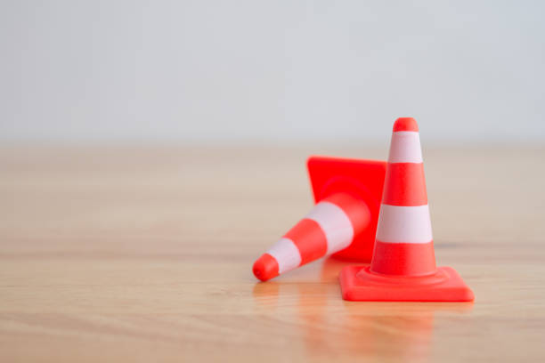 Close up orange white traffic warning cone or pylon on wooden table background with copy space. Attention, under construction, maintenance or repair, warning sign concept.