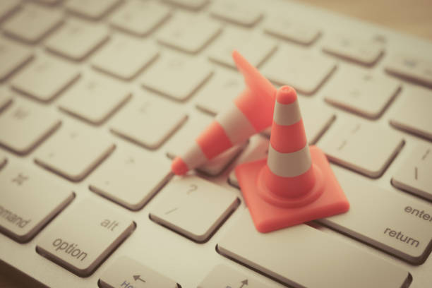 istock Close up orange white traffic warning cone or pylon on keyboard computer background with copy space. 1618681502
