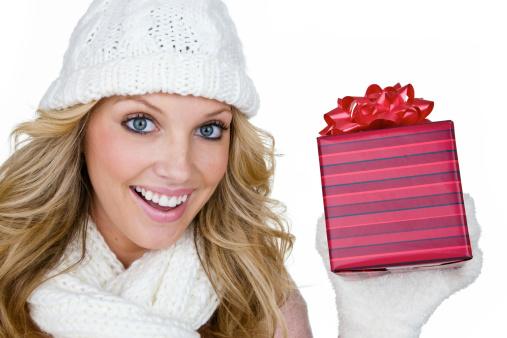 Cute blond woman wearing winter cloths and holding a gift while being isolated on white background