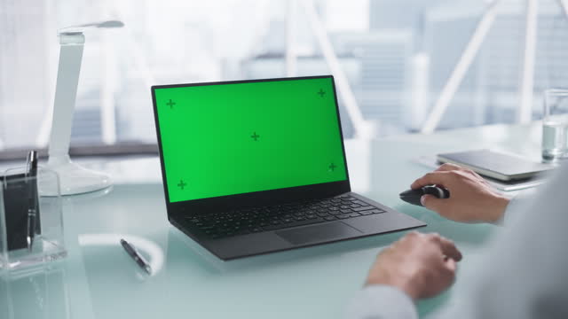 Anonymous Office Worker Working on a Laptop Computer with Mock Up Green Screen Chromakey Display with Motion Tracker Placeholders. Manager Analyzing Financial Results, Browsing Internet and Emails