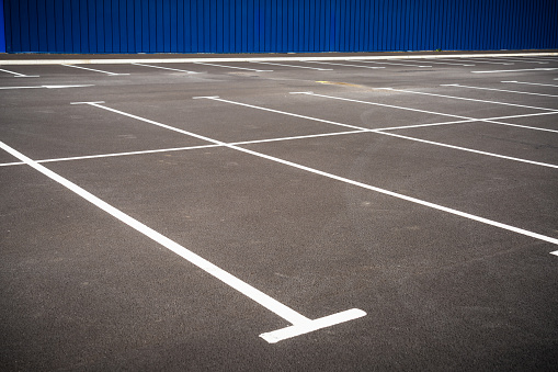 An empty outdoor car park with multiple spaces for cars.