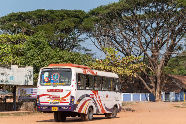 Mangalore, India - January 18 2023: A public transport bus parked at a bus station beside a park with tall green trees.