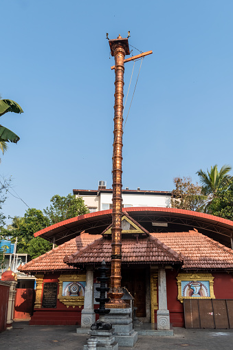 Mangalore, India - January 18 2023: The tall metal pillar outside an ancient traditional Hindu temple in a village near Mangaluru.