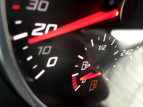 Low fuel gauge. Low fuel warning light in car dashboard