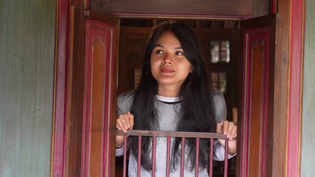 Beautiful asian  woman opening window in joglo house