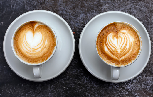 Cup of coffee latte or cappuccino art with heart shape drawing and beans isolated on white background